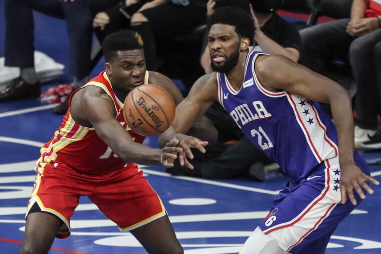 The Sixers' Joel Embiid eyeing a loose ball with the Hawks' Clint Capela during Game 5.