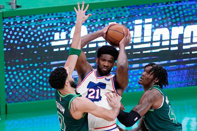 Joel Embiid (21) looks to pass while being pressured by Boston Celtics forward Jayson Tatum (left) and center Robert Williams during the first half Tuesday night in Boston.