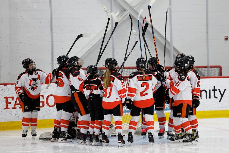 Philadelphia Liberties Black players raise their sticks before taking on the Nova Ice Dogs during the 2025 Liberties Invitational on Jan. 17 at the Flyers Training Center in Voorhees.