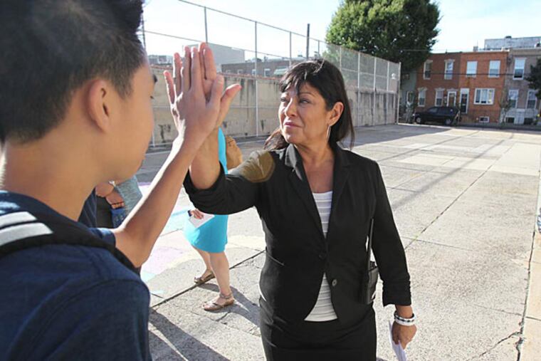 Principal Lisa Kaplan, right, high-fives with a group of 8th grade boys in the school yard at Andrew Jackson School at 1213 S. 12th St. in Philadelphia. ( CHARLES FOX / Staff Photographer )