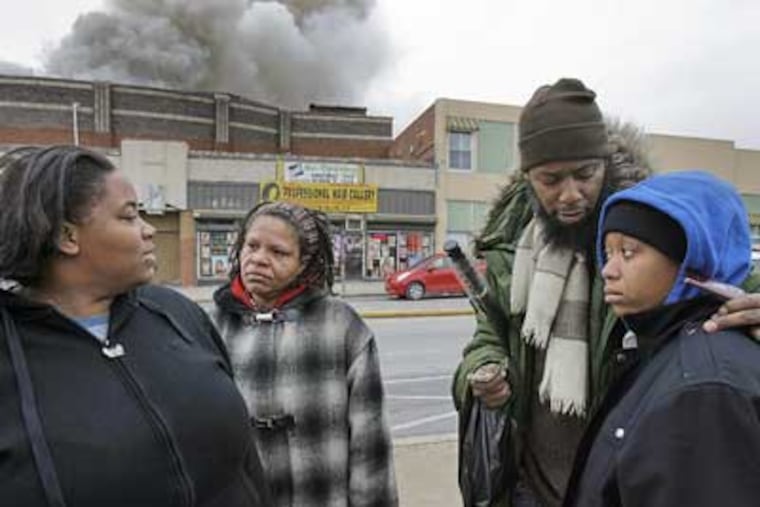 Residents of Grange Manor Apartments Theresa Fife (left) and her sister Cathy Lyles (right) are consoled by their mom Nana El (2nd from Left) and their brother Gregory Young near the fire scene on Broad Street on Saturday. (Akira Suwa / Staff Photographer)