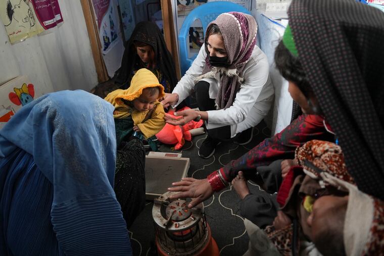 A nurse checks the weight of a child in the makeshift clinic organized by World Vision at a settlement near Herat, Afghanistan, Dec. 16, 2021. Malnutrition stalks the most vulnerable, and aid groups say more than half the population faces acute food shortages.