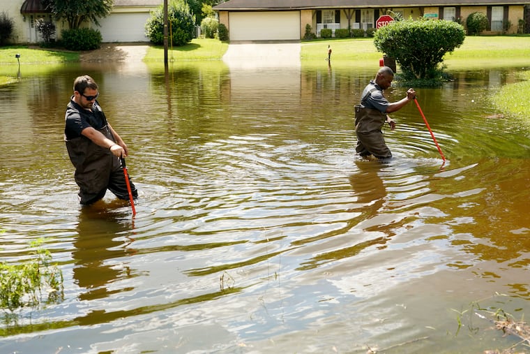 Emergency management workers wade through flood waters in Jackson, Miss. on Aug. 29. Flooding affected a number of neighborhoods near the Pearl River.