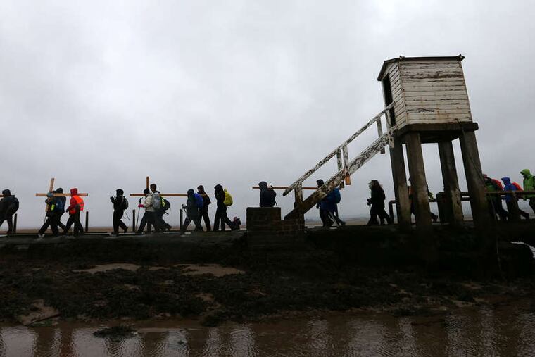 In England , pilgrims make the final leg of a 100-mile journey to Holy Island, Berwick Upon Tweed. The faithful have made the Holy Week trek for three decades. AP