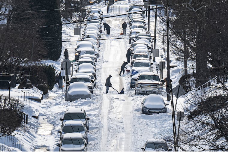 Residents shovel snow and dig out cars buried on a street in Haverford Township on Monday.