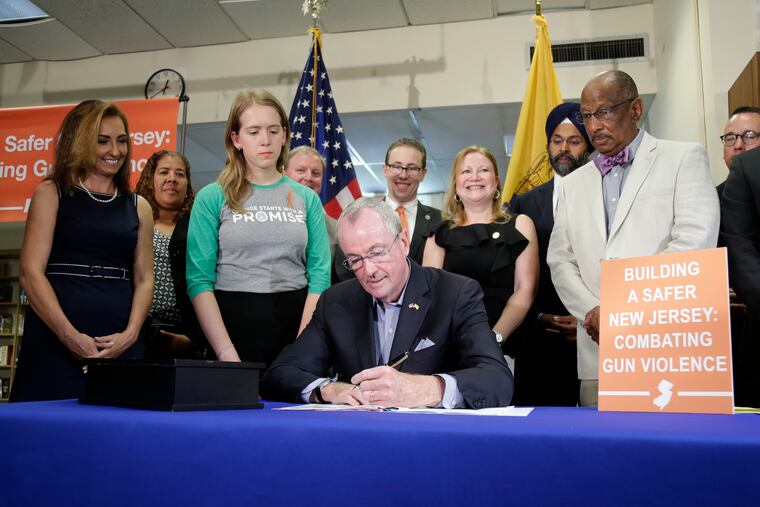 New Jersey Gov. Phil Murphy, center, signs a gun control bill during a ceremony in Berkeley Heights, N.J., Tuesday, July 16, 2019. Murphy has signed a measure aimed at making so-called smart guns available in the state. He also signed three other measures aimed at reining in gun violence.