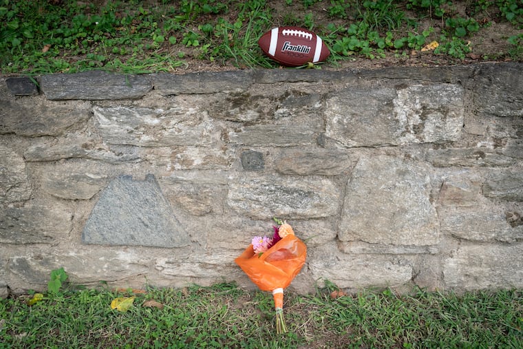 Flowers and a football sit outside of Roxborough High School near the football field at the end of the school day Wednesday.