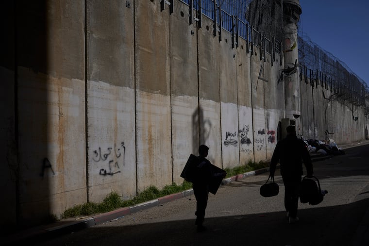 Palestinians walk along the separation barrier between the West Bank and east Jerusalem neighborhood of Beit Hanina, Sunday Feb. 15, 2026.