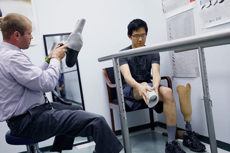 Yangzi Jiang, right, prepares for the final fitting of his running blade while Matthew Graham, a prosthetist at Cocco Enterprises, makes adjustments on Friday, June 13, 2014. Jiang received the running blade through Make A Wish Philadelphia & Susquehanna Valley. (Michael S. Wirtz/Staff Photographer)