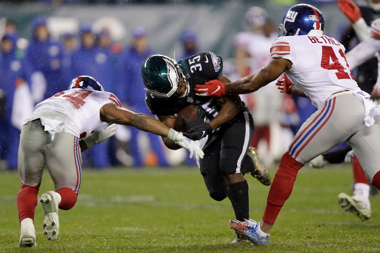 Eagles running back Boston Scott pushes through New York Giants free safety Antoine Bethea and New York Giants cornerback Julian Love on Monday, December 9, 2019 at Lincoln Financial Field in Philadelphia.