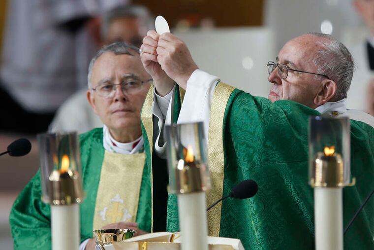 Pope Francis raises the host during Mass on the Benjamin Franklin Parkway. An event planner said 250,000 Communion hosts were prepared.