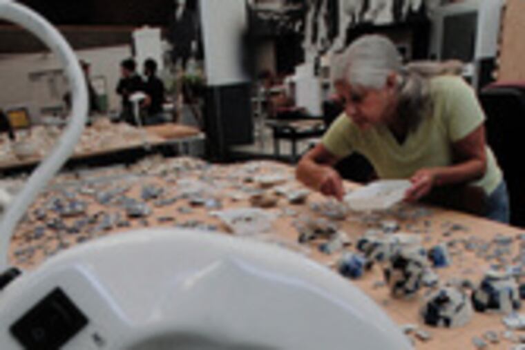 Volunteer Barbara Karp attempts to piece together porcelain fragments from an array of thousands. In the foreground is a partly reconstructed bowl.