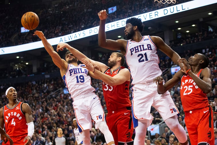 Sixers guard Raul Neto (19) jumps for a rebound in front of Toronto's Marc Gasol (33) as Joel Embiid (21) and Raptors' Chris Boucher (25) and Rondae Hollis-Jefferson (4) look on.
