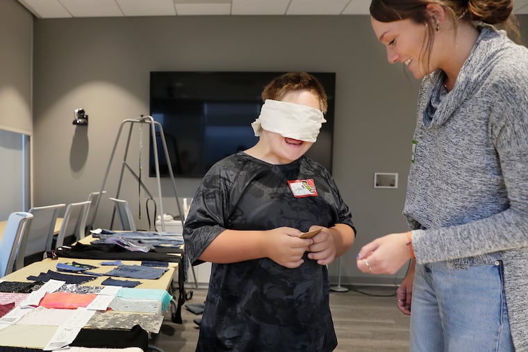 Univ. of Del. senior Elizabeth De Bruin helps 11 yr old Jayden Niblett of Seaford, DE explore the feel of different fabric swatches. Niblett was participating in the Down Syndrome Research Party at the Innovation Health and Design Lab at the University of Delaware in Newark, DE on October 27, 2019.