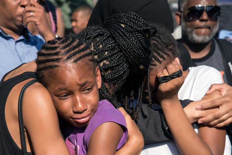 Family and friends comfort each other at the vigil for 15-year-old Tyhir Barnes on the corner of 58th and Ellsworth Street on Tuesday. Tyhir was killed Monday after a basketball game in Southwest Philadelphia.