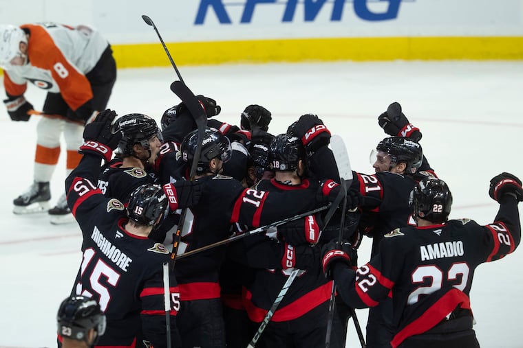 Flyers defenseman Cam York (8) skates past the Senators as they celebrate their overtime win in Ottawa.