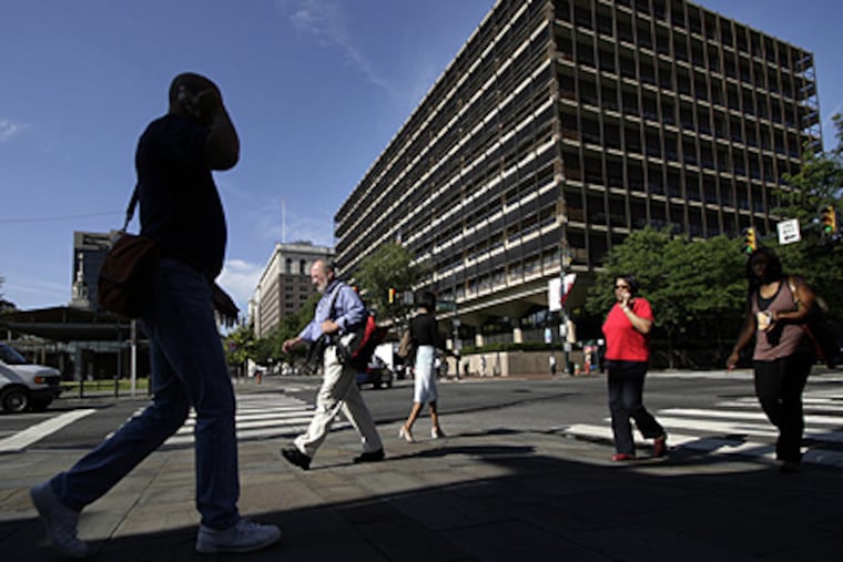 Pedestrians cross in front of the Philadelphia headquarters of Rohm and Haas. The company has reached an agreement to be acquired by Dow Chemical for $15 billion. (Laurence Kesterson / Inquirer)