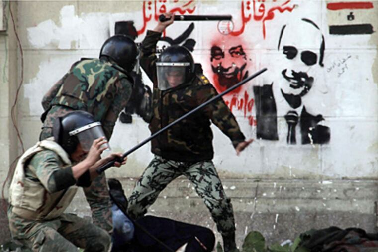 Egyptian soldiers beat a protester wearing a Niqab, an Islamic veil, during clashes near Egypt’s Cabinet building on Friday. (Ahmen Ali / Associated Press)