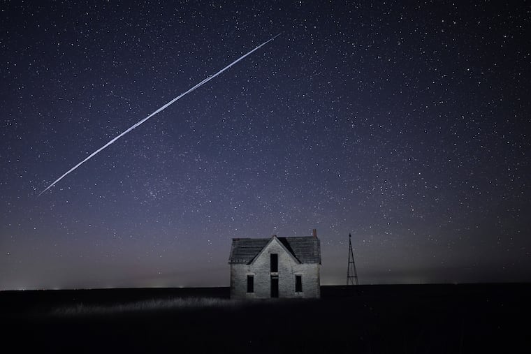 In this photo taken with a long exposure, a string of Elon Musk's SpaceX StarLink satellites passes over an old stone house near Florence, Kan. Some in the Philadelphia area have reported sightings of Musk's internet satellites.