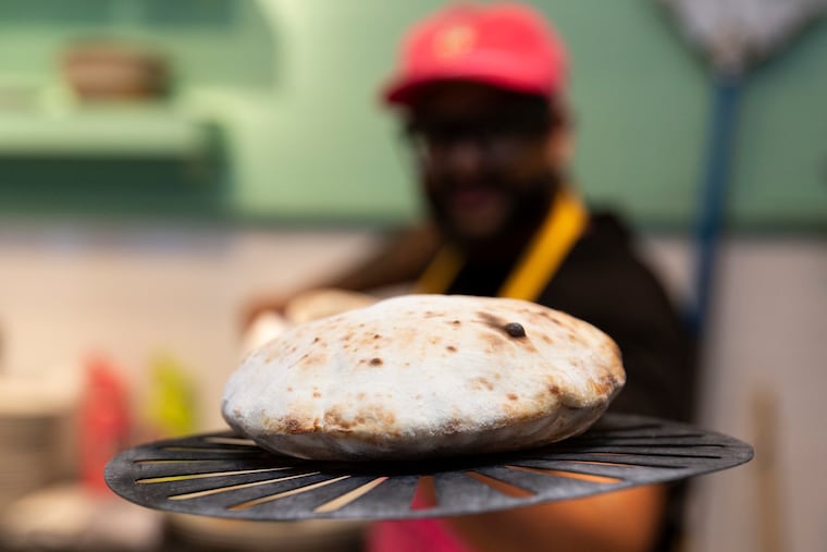 Chef Reuben R. Asaram takes naan from the oven during a Sunny’s Table dinner at Kampar in Philadelphia on Thursday, July 11, 2024. Kampar is located at 611 South 7th Street.
