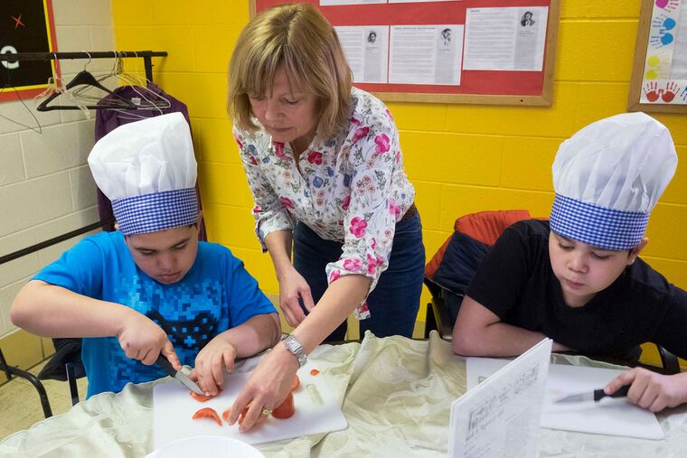 Teacher Jeanne DeVine watches Kevin Melendez as he cuts a red pepper while Devin Santana waits.