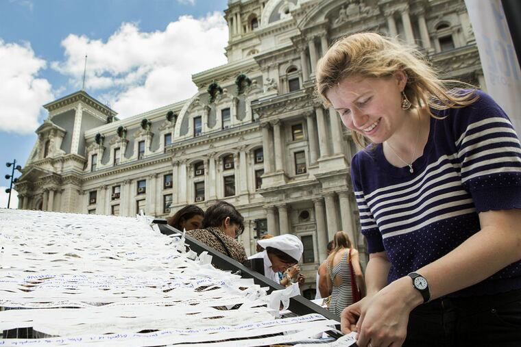 Sofai Seidel, an assistant at the Meg Seligman Studios, assists participants with a large public art exhibit for the Pope's upcoming visit. (Jessica Griffin/Staff Photographer)