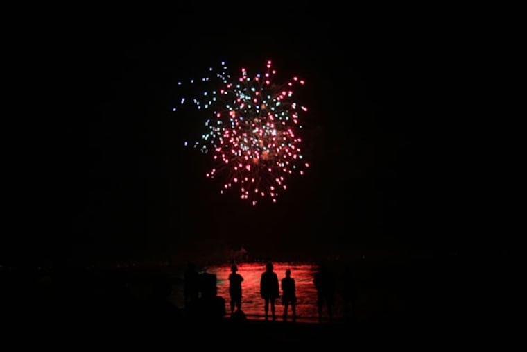 Spectators stand in the water at Ocean City, N.J. to watch the Fourth of July fireworks in 2018.