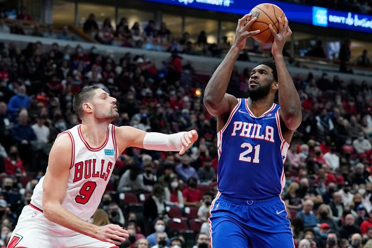 Philadelphia 76ers center Joel Embiid, right, drives to the basket against Chicago Bulls center Nikola Vucevic during the first half of an NBA basketball game in Chicago, Sunday, Feb. 6, 2022.