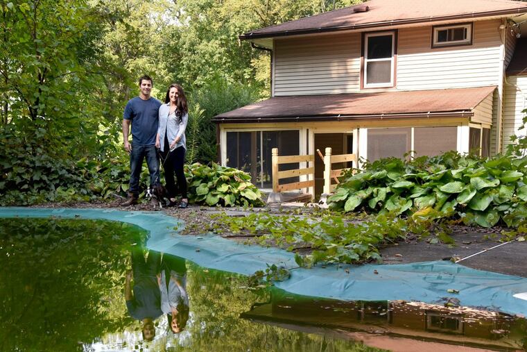 Rick Felix, his fianceé Amber Verazin, and their 2-year-old Boston terrier, Scarlet, check out the backyard at the foreclosed split level they just purchased in Ambler.