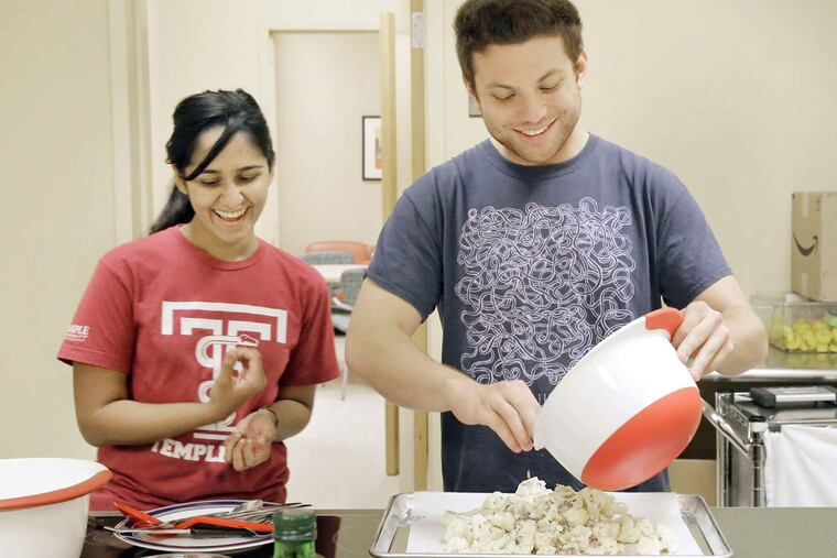 Medical students Bushra Anis and David Pioquinto make rosemary chicken drumsticks and cauliflower.