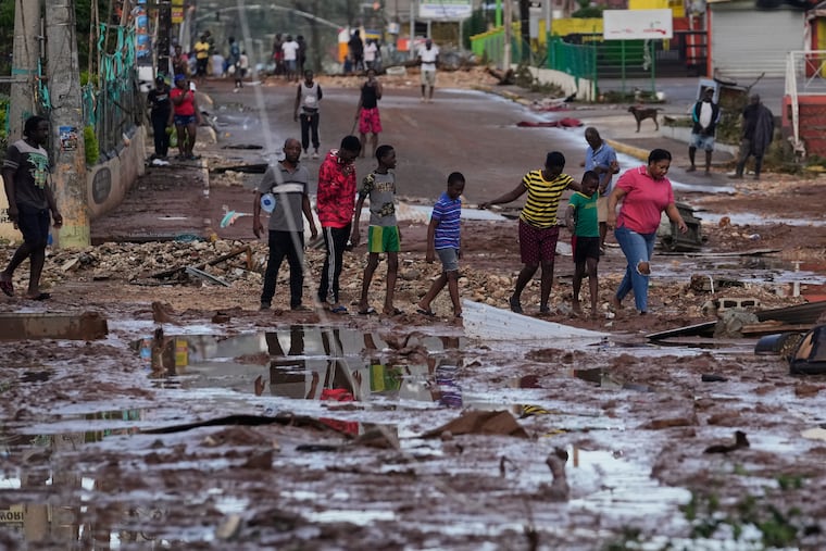 People walk through Santa Cruz, Jamaica, on Wednesday after Hurricane Melissa passed.