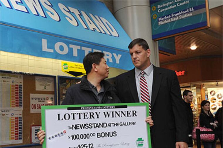 Owner (left) of the Newsstand at the Gallery collects a big check from Lottery Executive Director Todd Rucci for having sold the winning ticket. (April Saul / Staff Photographer)