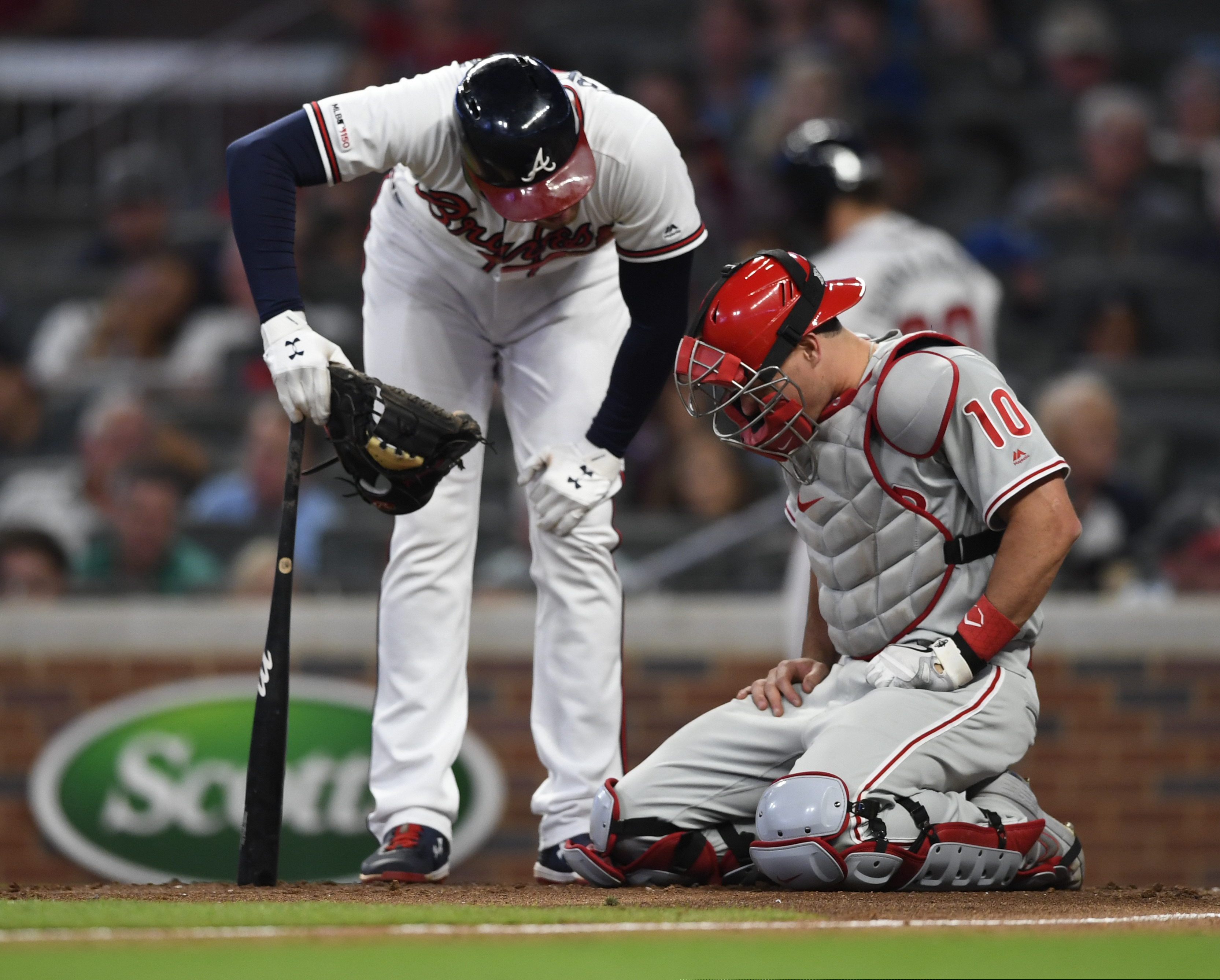 Philadelphia Phillies catcher J.T. Realmuto (10) pauses as Atlanta Braves' Freddie Freeman checks on him after he was injured with Freeman batting during the fifth inning of a baseball game Saturday, June 15, 2019, in Atlanta. Realmuto remained in the game. (AP Photo/John Amis)
