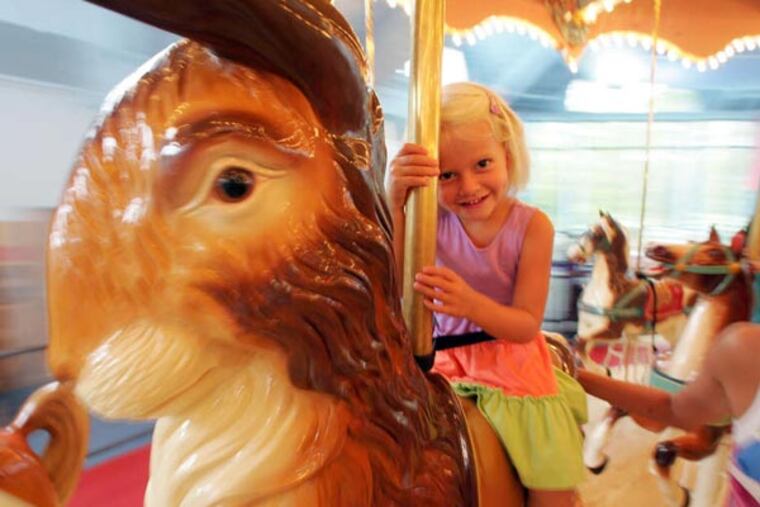 Camryn Thompson, 4, with her mother Jana rides the carousel at the Please Touch Museum. ( David Swanson / The Philadelphia Inquirer )