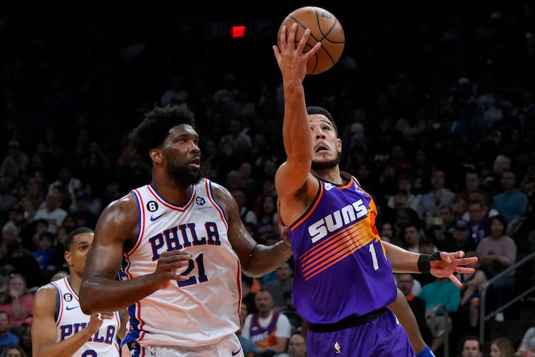 Suns guard Devin Booker (1) shoots as Joel Embiid defends during the second half Saturday.