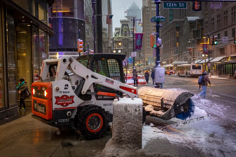A BobCat with brush sweeps snow off the side walk at 12th and Market St. in Center City, Philadelphia. Snow fell overnight covering the city and region on Friday morning March 1, 2019.