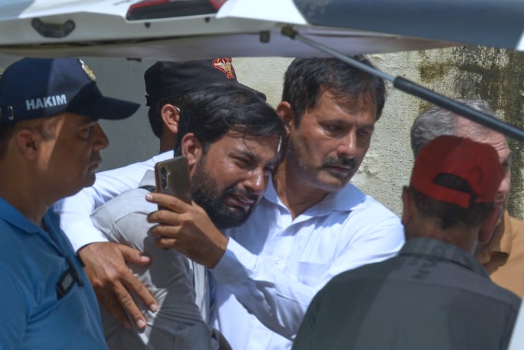 A father, center, of a victim in a fire, is comforted as his child's coffin is carried outside a hospital in Islamabad, Pakistan, Wednesday, Aug. 26, 2026. (AP Photo/M.A. Sheikh)