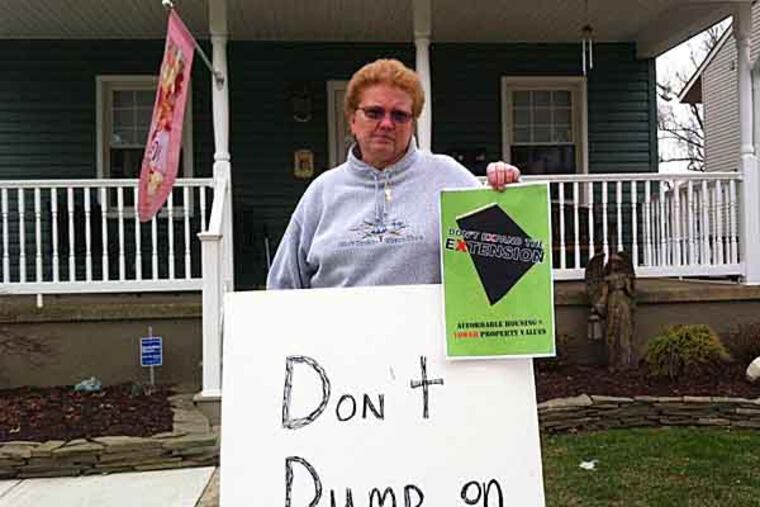 Regina "Jean" Bridges holds anti-affordable housing signs in front of her home in the West Collingswood Extension section of Haddon Township. Photo by Kevin Riordan
