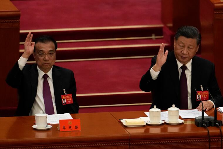Chinese President Xi Jinping looks over as Chinese Premier Li Keqiang raises his hand to vote at the closing ceremony of the 20th National Congress of China's ruling Communist Party at the Great Hall of the People in Beijing.