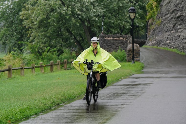 A woman in a rain coat rides her bike along Kelly Drive in the rain on August 9, 2024. After the driest October in Philadelphia on record, she may need to whip it back out after some drizzles on Nov. 1.
