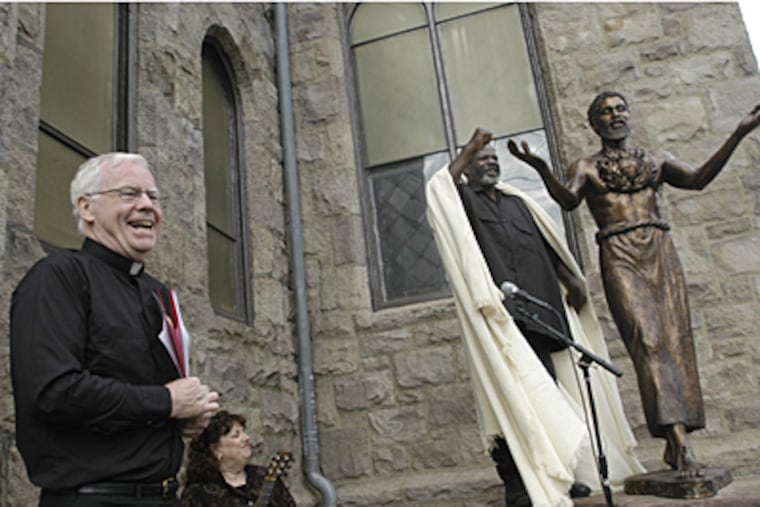 At Sacred Heart Church in Camden, Father Michael Doyle, left, grins as Willie Barnes unveils the statue of a black Jesus that was created by Father Leonard Carrieri. (April Saul / Inquirer)