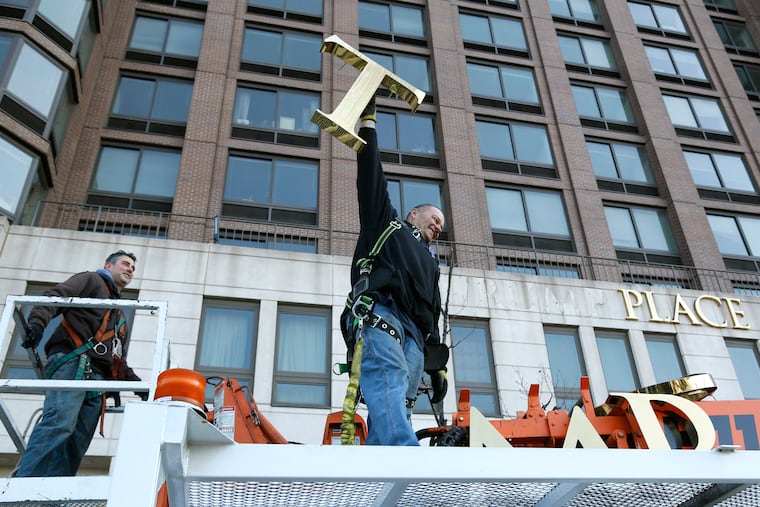 FILE- In this March 16, 2016, file photo, one of the workmen holds up the letter "T" as they remove the letters from a building formerly known as Trump Place in New York. Owners of the last of six luxury New York City condominiums that once displayed the president's name have voted to have name removed from the building. On Friday, Feb. 22, 2019, apartment owners got an email from the board of managers of a high-rise on Manhattan's west side confirming that "Trump Place" will disappear from the facade.