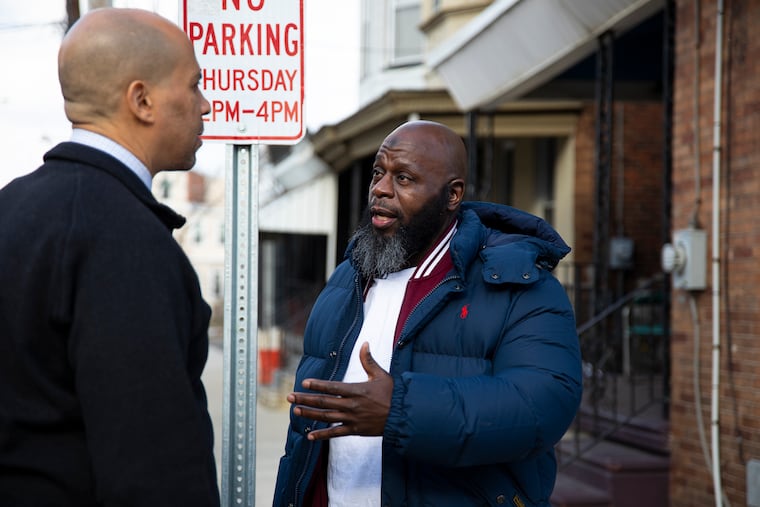U.S. Sen. Cory Booker meets with Simian Paulk, 50, of Camden, N.J., outside his home. Paulk is one of the first from New Jersey released under the “First Step Act” that Booker help get passed.