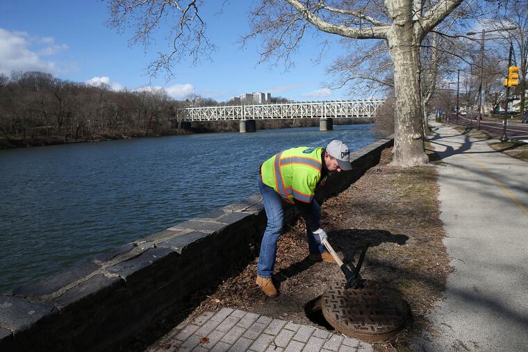 Philadelphia Water Department customer service supervisor Joe Ferretti closes a manhole after showing where stormwater drains into the Schuylkill at Midvale Avenue and Kelly Drive in East Falls on March 16, 2018. Stormwater infrastructure is one area where Philly can step up environmental efforts, writes Lena Smith of PennFuture.