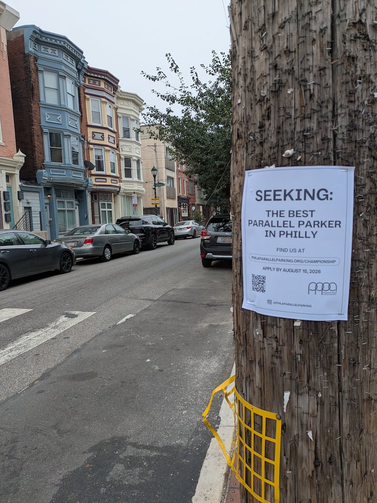 A sign advertising the 2026 Philadelphia Parallel Parking Association Championship is affixed to a pole across from some fine examples of parallel parking in the city.