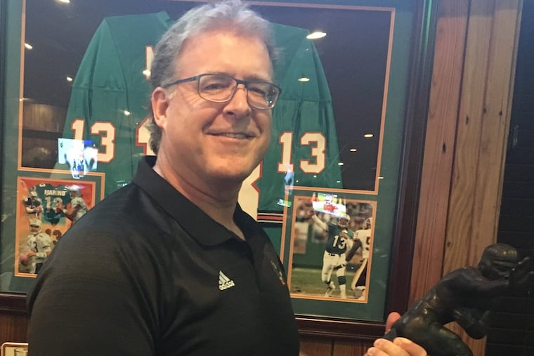 Former Shawnee and University of Miami football star Gregg Rakoczy, here holding former Miami quarterback Gino Toretta's Heisman Trophy, will be indicted in the Shawnee Hall of Fame on Friday, Sept. 28, 2018.
