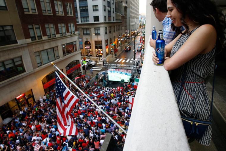 Kristia Jenkins and Matt Stevens watch the World Cup Soccer match between the United States and Portugal from a parking structure alone the 1500 block of Locust Street in Center City on Sunday, June 22, 2014. (Yong Kim/Staff Photographer)