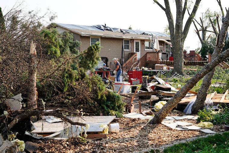 People clean up debris in front of a damaged home after a tornado struck the day before, Tuesday, July 28, 2026, in Appleton, Wis. (AP Photo/Kayla Wolf)
