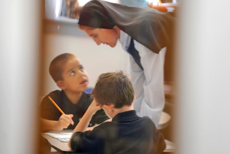 Seen through their first-grade classroom door window, Sister Maria de Jesus helps Christopher Pagan (left) and Joseph McDermott, both 6, with their classwork at St. Peter's School in Merchantville, September 30, 2013. The school has implemented Robert Healey's Catholic School Development Program, which has been credited with helping Catholic schools in South Jersey and Philadelphia improve enrollment, raise funds and improve academics. (TOM GRALISH / Staff Photographer)