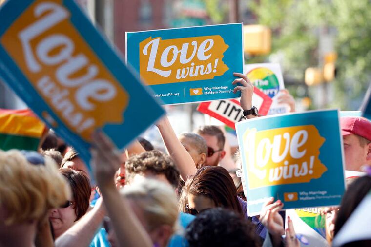 People hold up signs and cheer at City Hall on Tuesday to celebrate the overturning of Pennsylvania's gay-marriage ban.